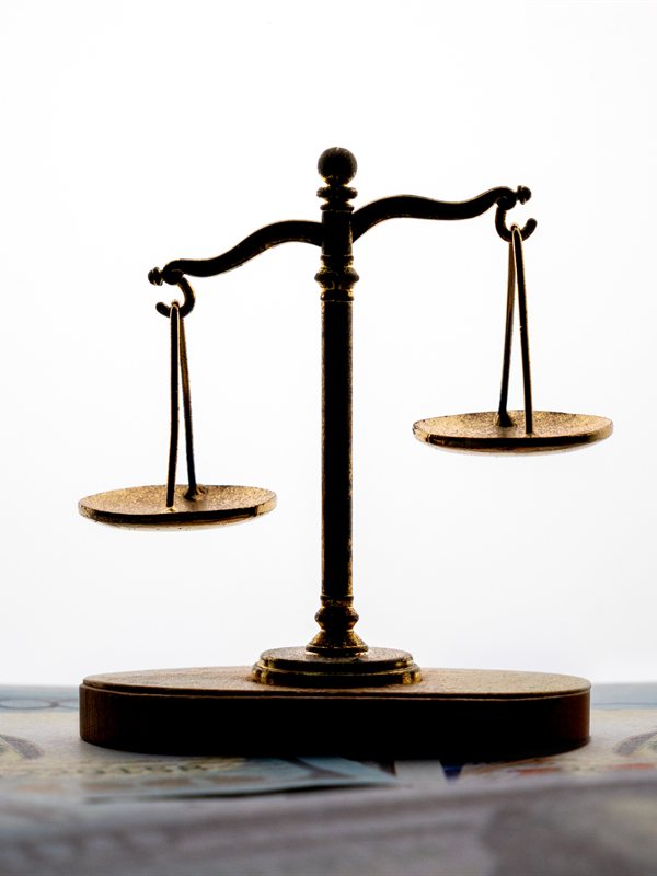A brass balance scale resting on currency