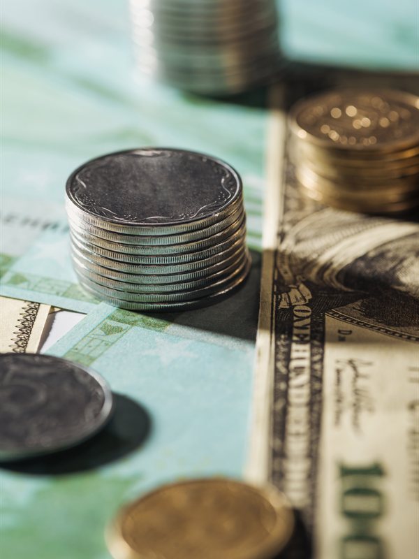 Stacks of coins beside a hundred-dollar bill