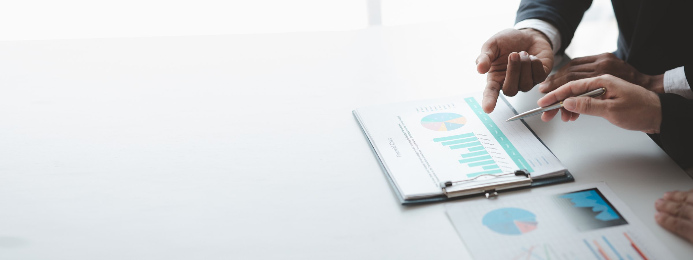 Two professionals reviewing financial charts on a clipboard